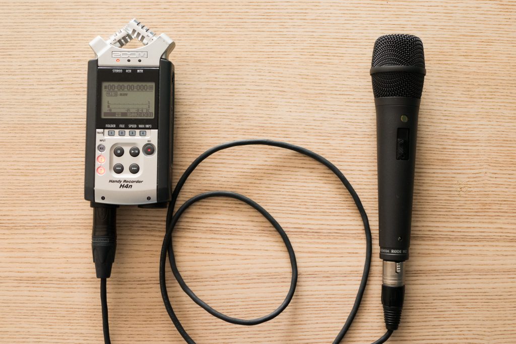 Mikrofon do nagrywania podcastów podłączony kablem XLR do rejestratora dźwięku.