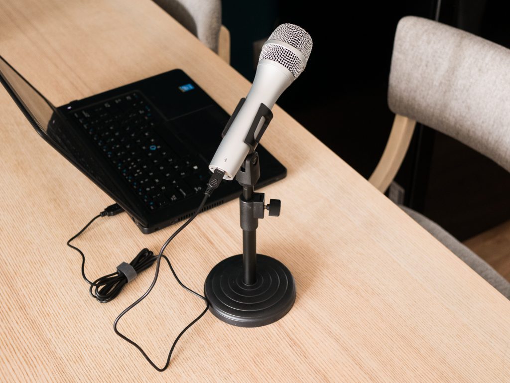 Zestaw do nagrywania podcastów. Mikrofon USB podłączony kablem do laptopa.